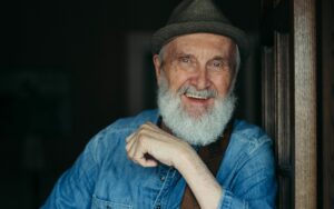 Fred Penner from ‘The Cat Came Back’ performance wearing a denim shirt and grey fedora smiling at the camera