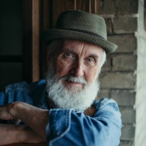 Fred Penner from ‘The Cat Came Back’ performance close up wearing a denim shirt and grey fedora