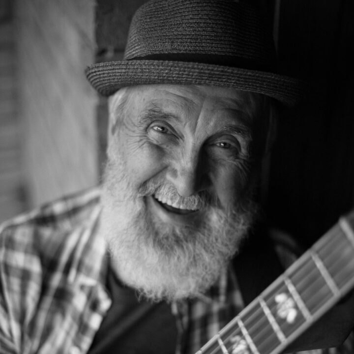 Black and white photo of Fred Penner from ‘The Cat Came Back’ performance smiling at the camera