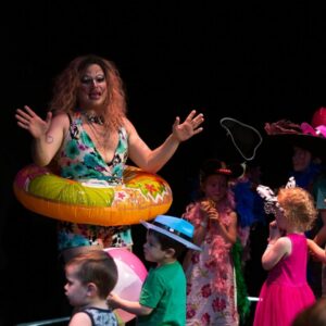 Image of a group of children standing in front of a performer wearing a pool floatie from the Parents are still a Drag performance