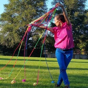 Image of woman in pink holding many strands of colourful yarn above her head during our Tricoter performance