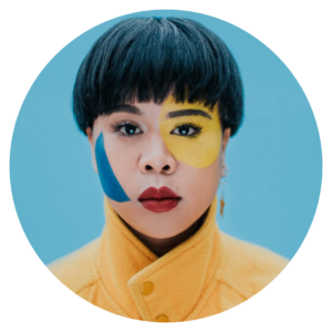 Image of Kimmoral with blue and yellow face paint. They are a featured artist in the future artists performance on June 3rd