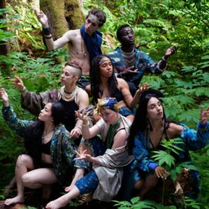 Performers from the Living With performance wearing blue in a green forest looking at the plants
