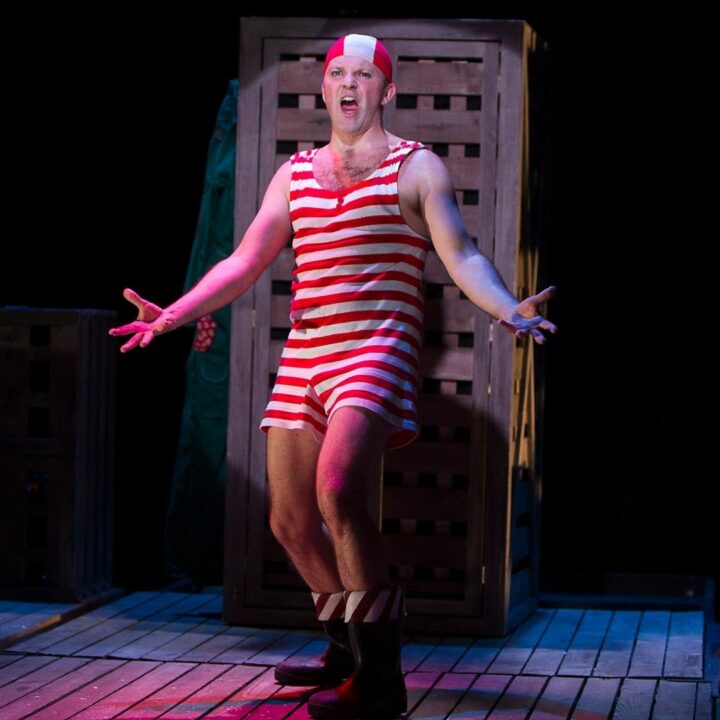 Image of performer in red and white stripes singing. From The Girl who Forgot to Sing Badly performance, available online from May 31st-June 12th