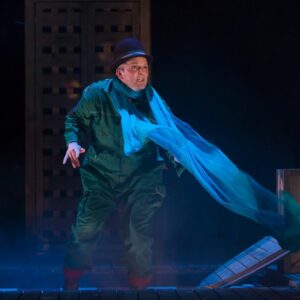 Image of a performer wearing a green jumpsuit and long blue scarf. From The Girl who Forgot to Sing Badly performance, available online from May 31st-June 12th