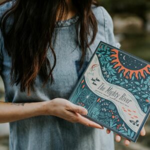 Image of Ginalina wearing a blue denim shirt and holding her book, The Mighty River