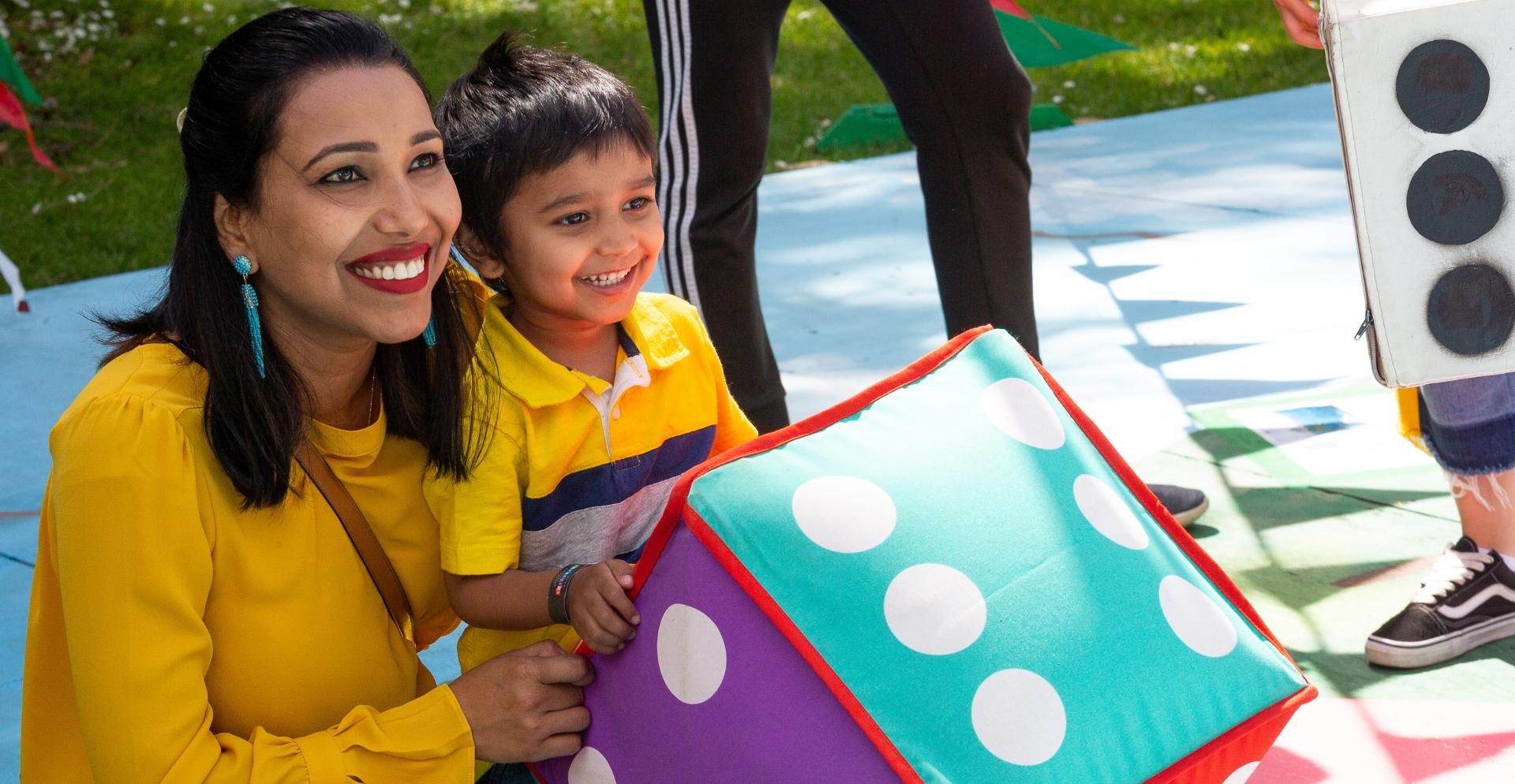 Image of a woman and little boy dressed in yellow, smiling.