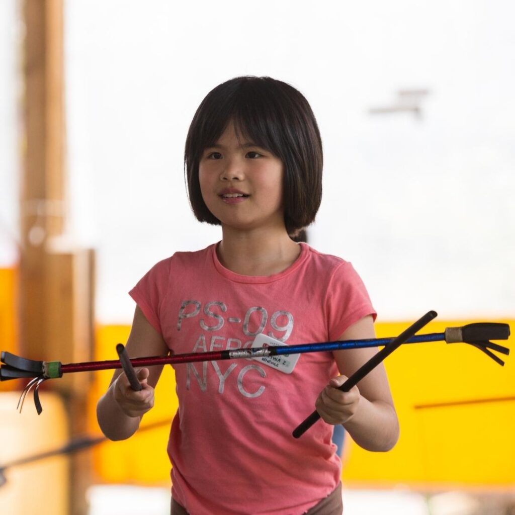 Image of young girl smiling holding sticks