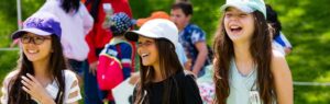 Image of three girls in hats laughing in the sun