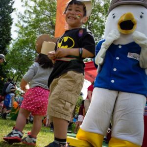 Child in facepaint smiling beside Salty the Seagull mascot