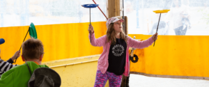 Girl in pink balancing plates on two sticks