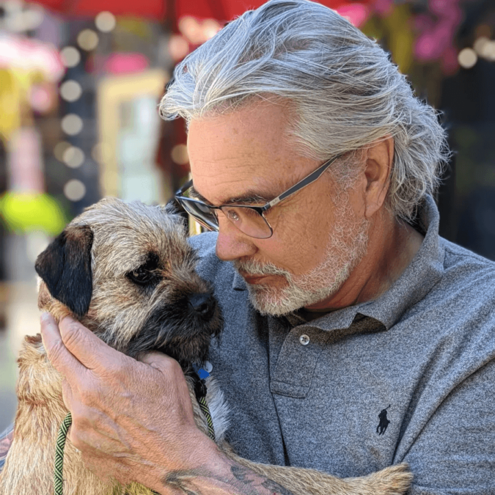 David Bouchard in a grey polo shift holding their dog