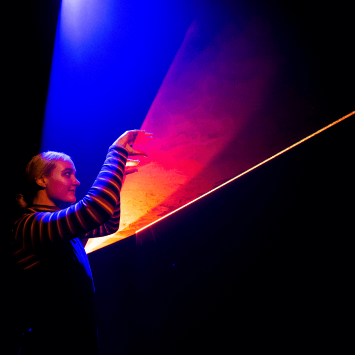 a performer in a dark room, with orange and red light