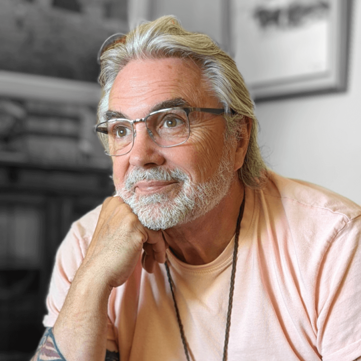 David Bouchard sitting and resting his head on his hand, while wearing a light peach colored shirt