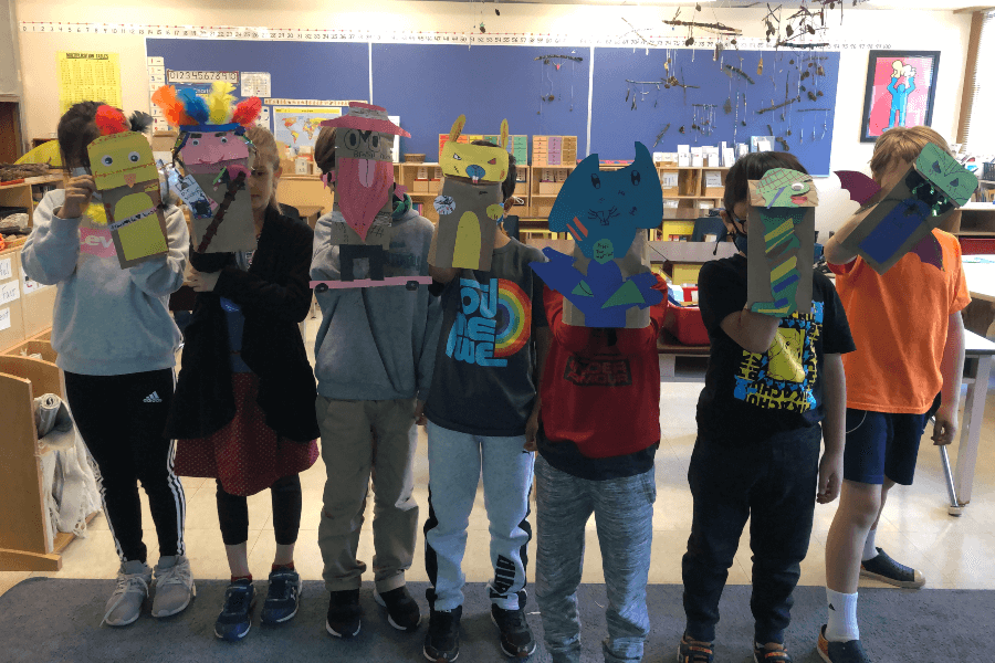 Elementary school students holding up paper bag puppets that they made at a past workshop