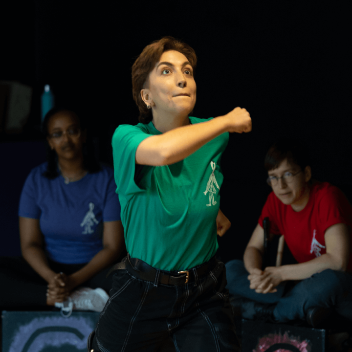 a performer wearing a green shirt, with two performers in the background