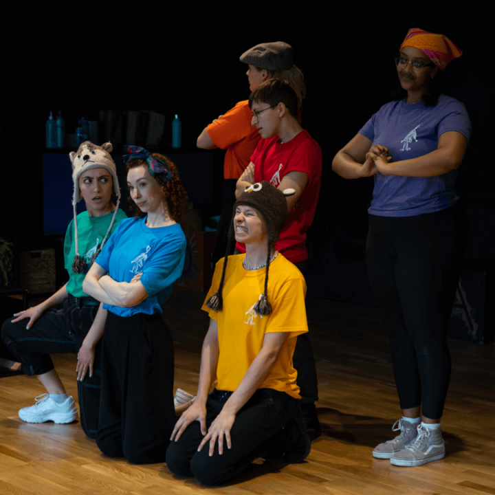 6 performers on stage, 3 of which are standing, and the other 3 are kneeling