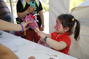 a child with pink face paint participating in arts and crafts