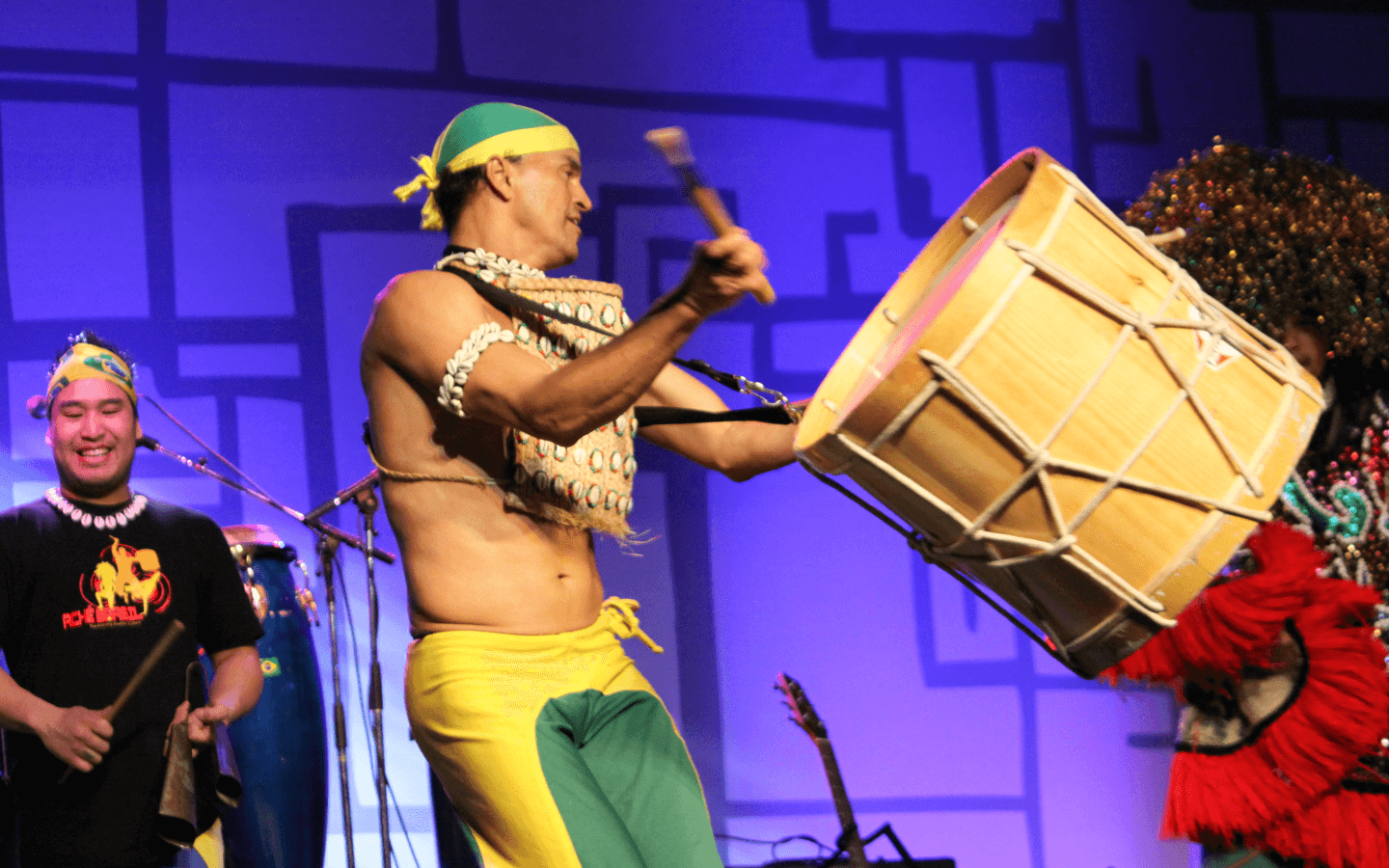 man playing the drums on stage with a man in a black shirt