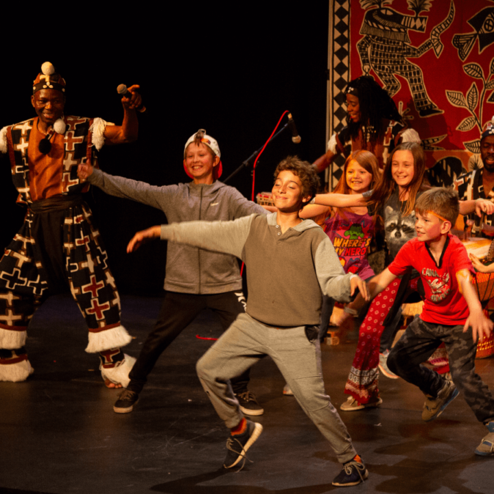 a group of children on stage dancing with the show performer