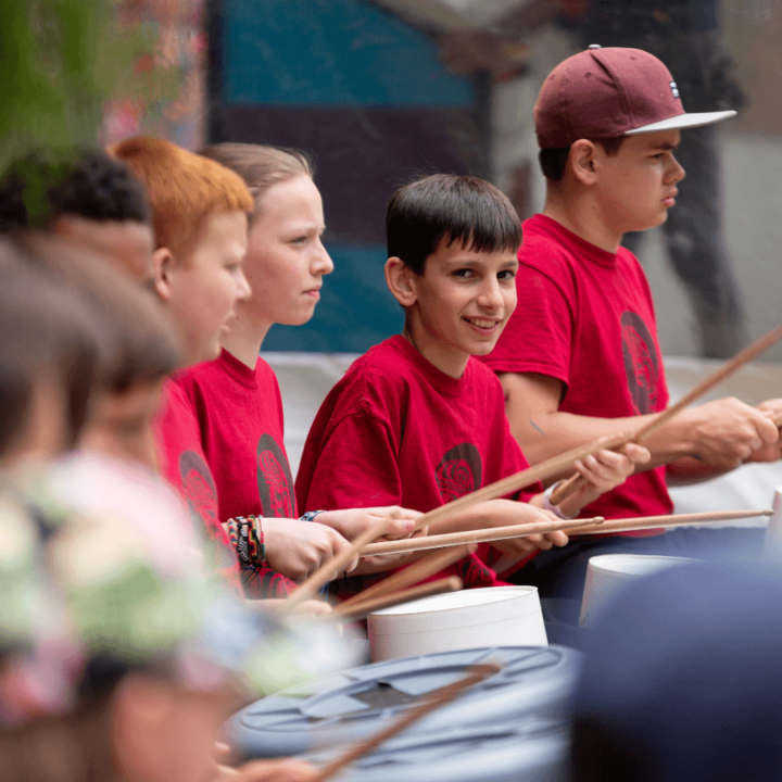 children smiling while playing indigenous drums