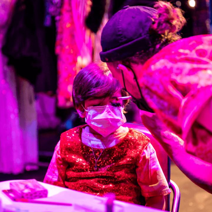 A performer from Glamily talking to a child, and helping them with their dress-up accessories