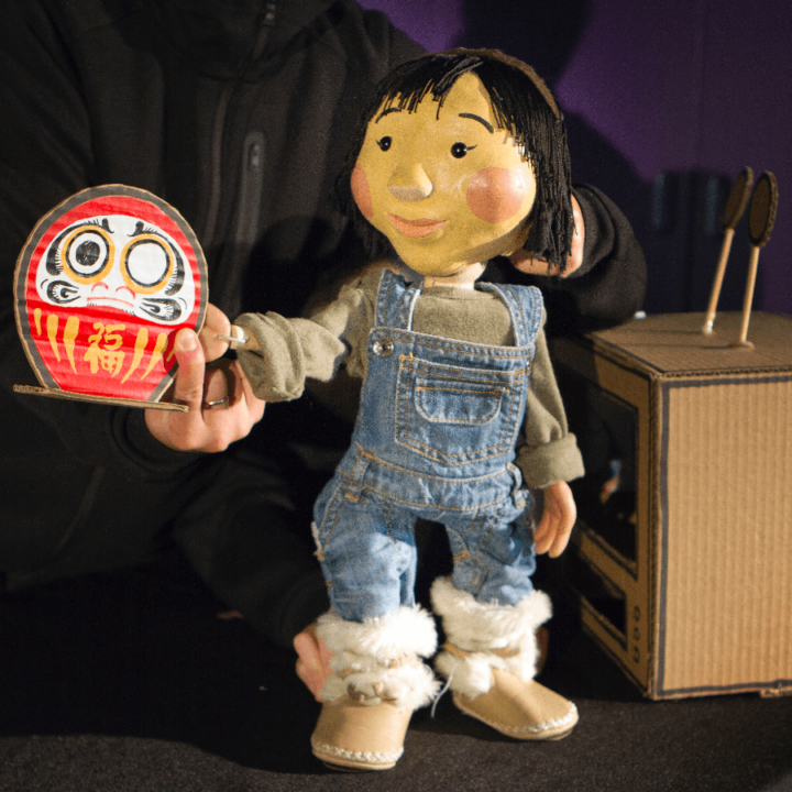 A little girl puppet wearing jean overalls