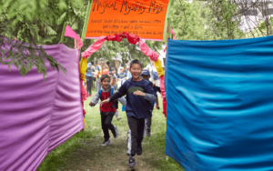 A group of children running through a tunnel like maze with brightly coloured fabric walls.
