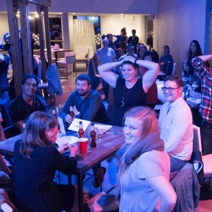 A group of people at an evening event. Some have their hands on their heads.