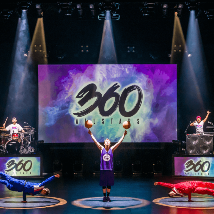 360 AllStars dancers perform on stage. The words 360 AllStars is projected behind them on a screen.