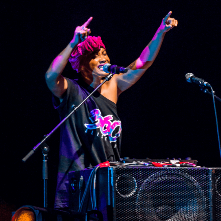 A woman on stage with a microphone and a dj box.