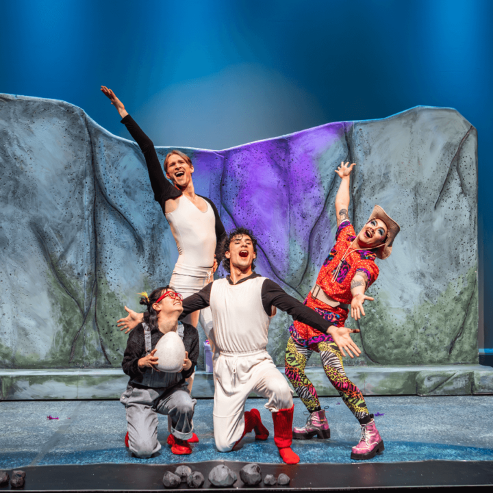 Four perfomers singing on stage; one of the holds an egg.