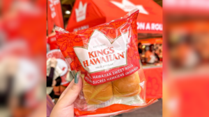 A hand holding a package of King's Hawaiian Sweet Rolls.