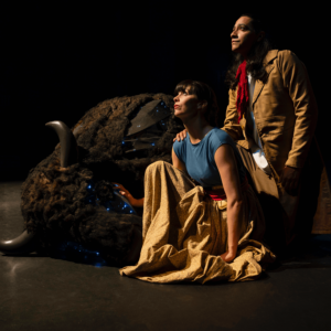 Marie and Louis kneel beside the buffalo. They are both looking up at the stars.