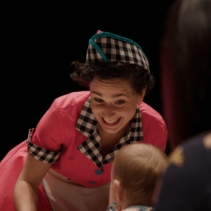 Dottie is bending down and smiling at a toddler.